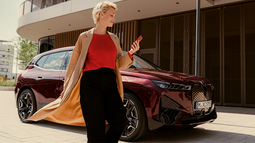 My BMW App Žena s pametnim telefonom ispred BMW-a Žena s pametnim telefonom ispred BMW-a