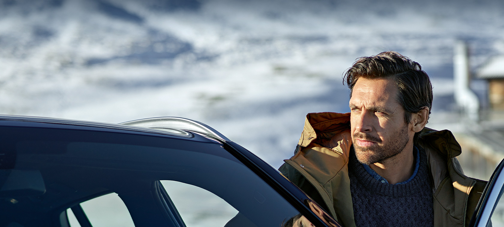 Originalni BMW dodaci i BMW usluge za jesen i zimu Muškarac u zimskoj parka jakni stoji ispred vrata svog BMW-a